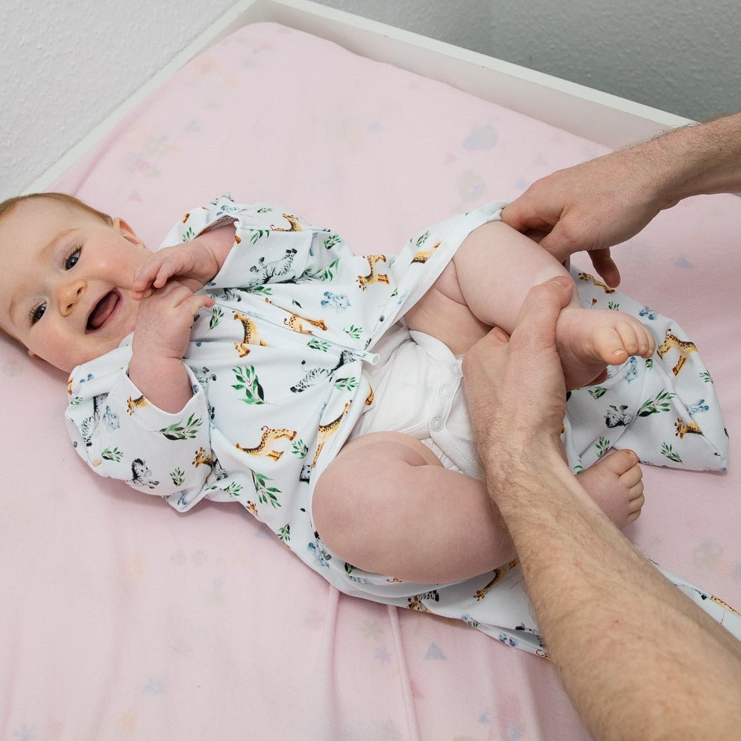 Baby wird angezogen mit Vorteil des Zwei-Wege-Reißverschlusses